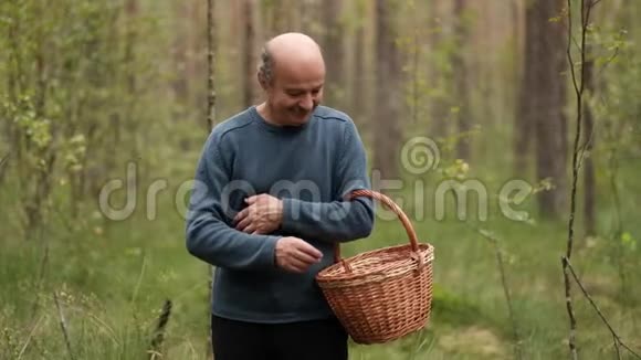 一个在森林里拿着篮子的成熟男人手里拿着几个蘑菇视频的预览图