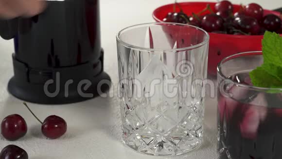 带冰和薄荷的樱桃汁放在碗里的樱桃放在白色背景的女人的手视频的预览图