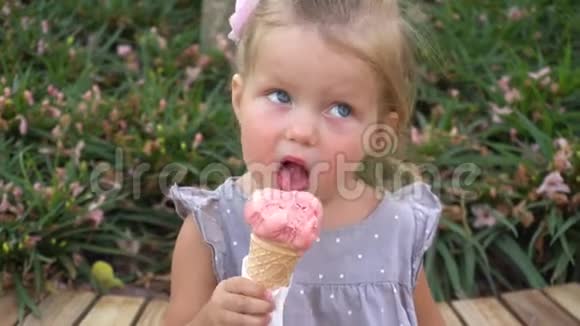 在公园里吃粉色冰淇淋的小女孩视频的预览图