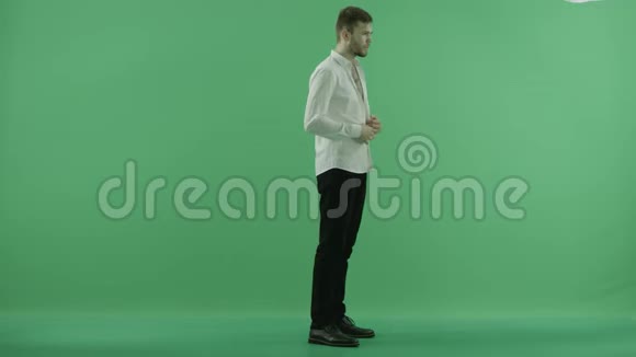 年轻人把衬衫扣在绿色的背景上视频的预览图