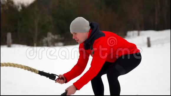 男子用绳子在功能性训练中健身冬季在交叉健身中锻炼慢动作视频的预览图