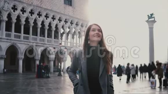 美丽的年轻欧洲妇女游客微笑兴奋地走在旧古董圣马可城广场在威尼斯意大利视频的预览图
