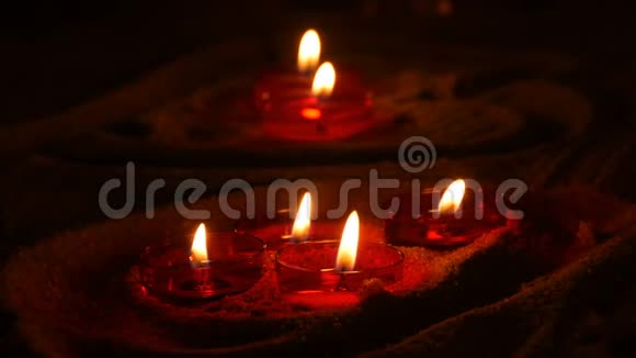在一个天主教的寺庙里红色的圆形燃烧的葬礼蜡烛在沙子上黑暗中的烛光视频的预览图