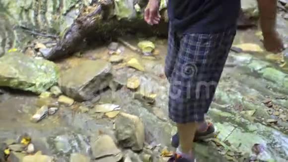 旅人的腿在森林中的山溪上从石头移动到石头视频的预览图