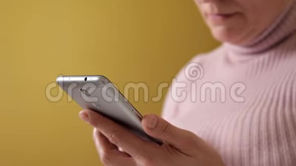 一个戴眼镜的女人在家里抱着一个白色枕头坐在沙发上在她全新的智能手机上写着信息视频的预览图