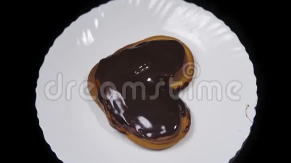 心形的发髻巧克力被覆盖躺在白色的盘子上在黑色的背景上旋转视频的预览图