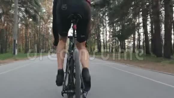 后面跟着一个穿着黑色衣服骑自行车的运动型自行车运动员腿部肌肉发达骑自行车骑自行车视频的预览图