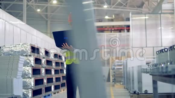 男性工人在他的笔记本电脑上打字站在一个仓库工业工厂视频的预览图