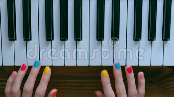 一个年轻积极的女孩有漂亮的手和彩色指甲弹钢琴视频的预览图