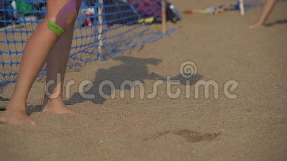 一个女人的腿和她的影子在沙滩上打排球视频的预览图