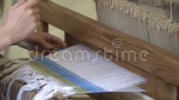 在织布机上把女人的手织成蓝色和白色的图案传统编织技术视频的预览图