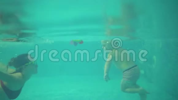 在水下拍摄的可爱的金发幼儿和他的母亲一起在游泳池下游泳然后视频的预览图