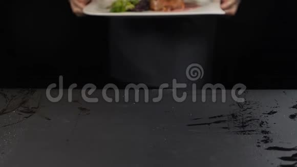 厨师端菜把一盘牛排和绿色沙拉放在桌子上厨师的手紧紧地举起高清奢侈品视频的预览图