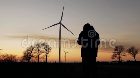 日落时分一个人的剪影为风力涡轮机拍照视频的预览图