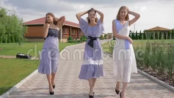 穿着时髦裙子走在公园人行道上的时髦年轻女性视频的预览图
