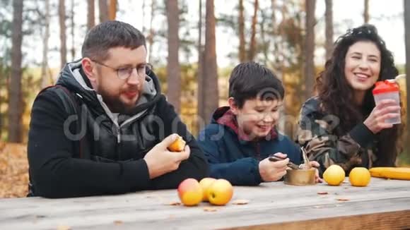 幸福的一家人在餐桌旁的树林里坐在一起享受着晚餐视频的预览图