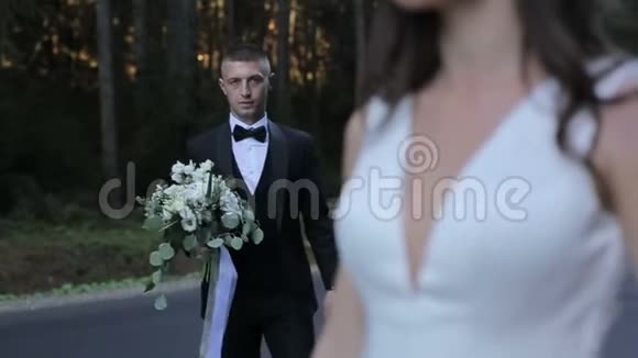 在路上结婚的情侣新郎带着一束鲜花去见新娘视频的预览图