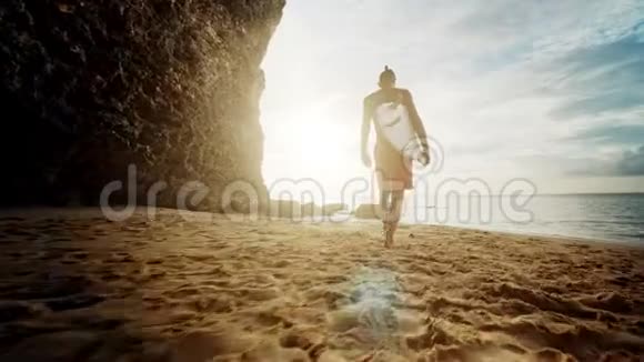 早上在海滩上散步的人巨浪崩塌一个穿着冲浪板的女冲浪者的剪影视频的预览图