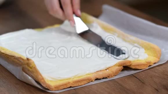 在家里做瑞士卷的时候把无法辨认的糖果摊铺奶油贴在海绵蛋糕上视频的预览图