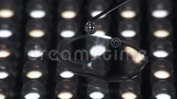近距离透明液体从注射器针头滴出隔离在灯光下视频的预览图