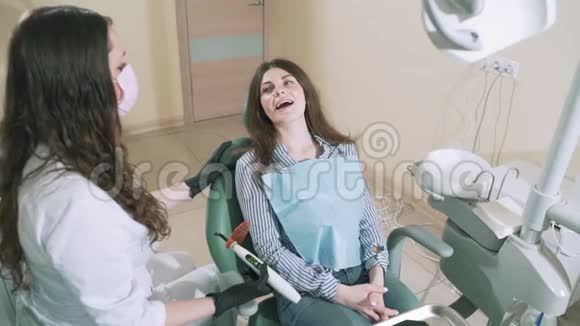 慢镜头拍摄女孩躺在牙科椅上微笑着一位女医生打算用一种现代的方法钻她疼痛的牙齿视频的预览图