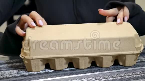 雌性手打开一个纸板蛋盒里面有十个鸡蛋环境包装概念视频的预览图