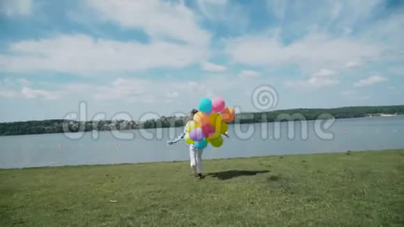 漂亮女孩带着五颜六色的气球跑到河湾视频的预览图