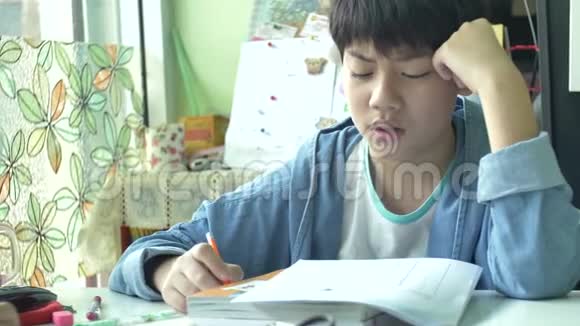可爱的亚洲男孩用愤怒的脸做作业的慢动作4K视频的预览图