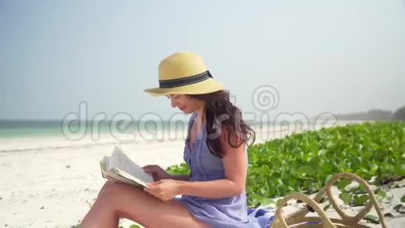 在海滩上看书的年轻白人妇女视频的预览图