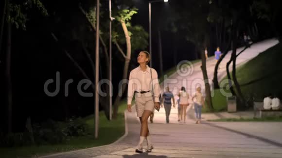年轻的现代女性走在公园的大街上晚上四处看热闹视频的预览图