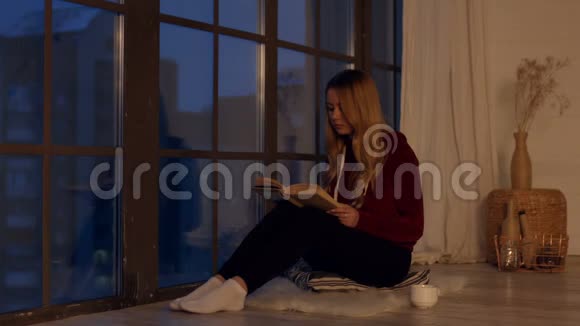 一个漂亮的年轻女人在家靠窗户看书视频的预览图