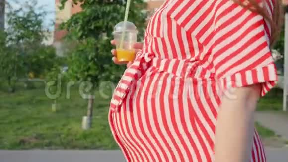 等待孩子的孕妇女人从稻草中喝橙汁在城市里散步的概念视频的预览图