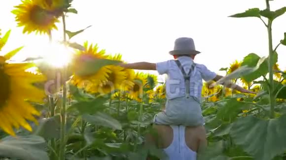 暑假少年女孩背着孩子背着向日葵穿过田野视频的预览图