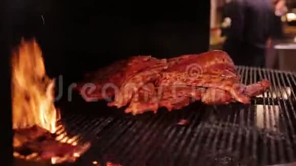 厨师把大块的排骨放在烤架上肉在一个大烤架里炒烤火的排骨视频的预览图