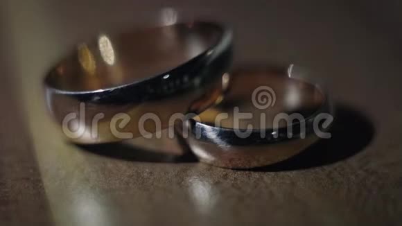 结婚戒指躺在桌子上在黑暗的背景下发光特写视频的预览图