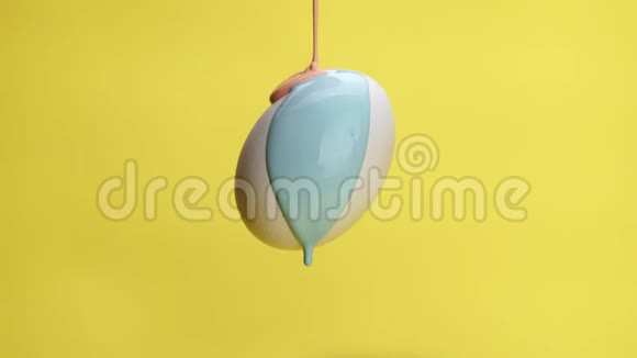 蓝色和粉红色的油漆在空气中的鸡蛋上流动视频的预览图