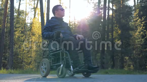 残障人士坐在森林旁边的电动轮椅上视频的预览图