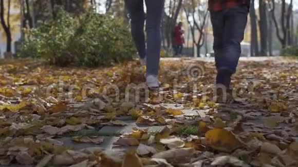在日落时分女人和男孩的腿紧紧地走在秋天的公园里视频的预览图