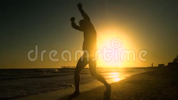 快乐的男人在海滩上跳舞他在阳光下跳跃这个人玩得很开心他很开心一个男人的剪影视频的预览图