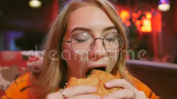 穿老虎服装的小女孩坐在咖啡馆里吃汉堡视频的预览图
