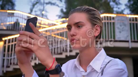 年轻的现代女性站在桥上在智能手机上拍摄日落发送它沟通概念梯子视频的预览图
