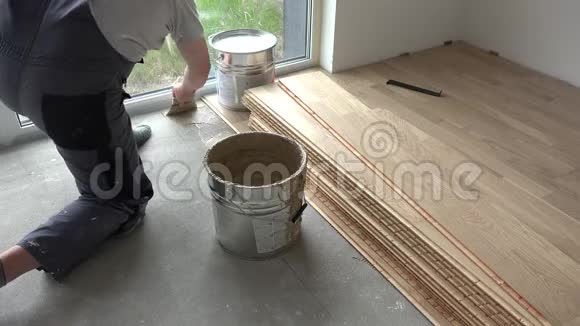 木工人在混凝土地面上涂胶粘剂工人安装木地板视频的预览图