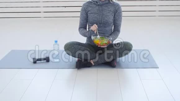 健康食品概念快乐的女人在白色的室内锻炼后吃健康的绿色沙拉视频的预览图