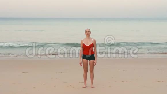 年轻健身女子马拉松运动员在日出前在热带海滩热身视频的预览图