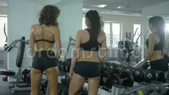 两个女健美运动员正在健身房里交谈从后面看视频的预览图
