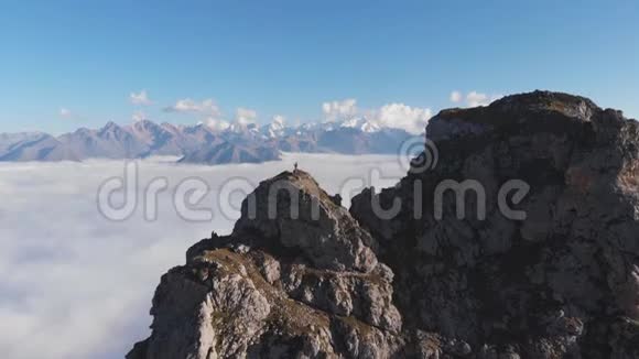 高空飞行的登山者在高高的云层之上的山顶上视频的预览图