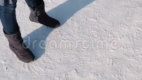 这位穿着靴子女子的特写在雪地上画出了图案视频的预览图