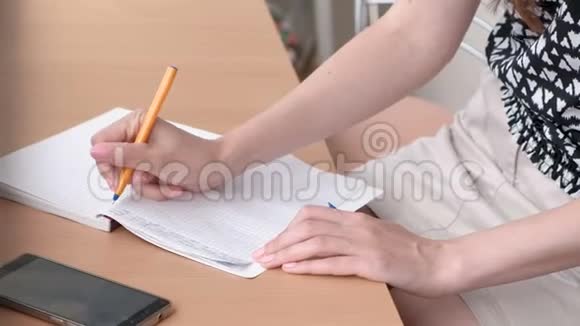 女人正在家里阳台上的笔记本上写一些东西特写女人手视频的预览图