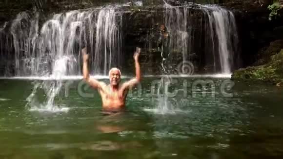 快乐老人享受瀑布的清凉视频的预览图