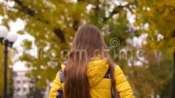 女孩走过秋天的公园风吹起了她的头发慢动作视频的预览图